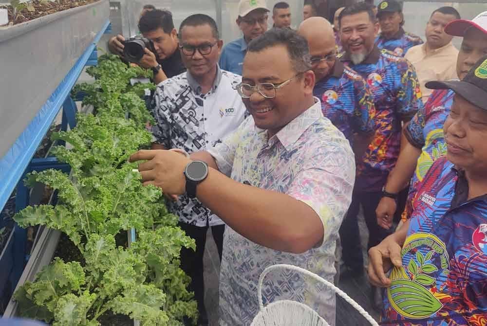 Amirudin (kanan depan) melawat kebun komuniti pada Majlis Perasmian dan Penyerahan Green House Projek Teknologi Microfarm di Kebun Komuniti Kampung Baru Batu Caves di sini pada Ahad.