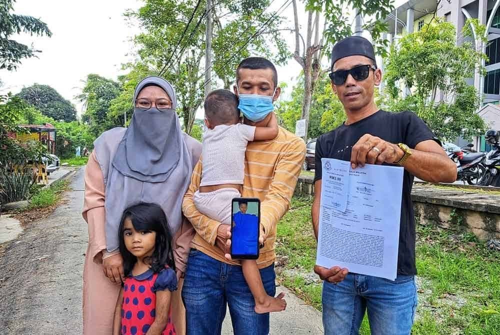 Ahmad Mudzakkir (tengah) menunjukkan laporan polis dan gambar anak lelakinya selepas menjalani pembedahan di HSB, Alor Setar pada Ahad.