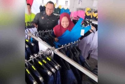 Lilis Saslinda (hadapan) melihat pakaian sekolah yang dijual sempena Program Jualan Rahmah 'Back To School', pada Ahad.