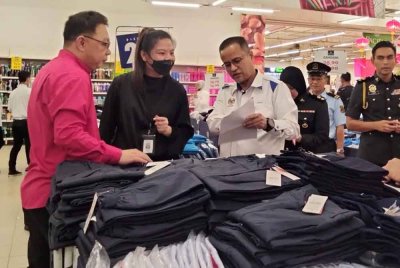 Azman (kanan) melakukan pemantauan harga pakaian sekolah di sebuah pasar raya di Kota Bharu pada Ahad.