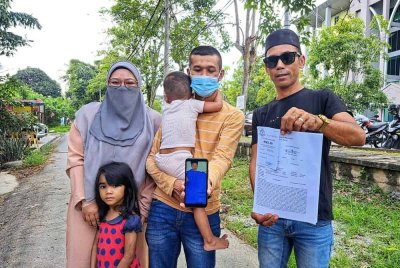 Ahmad Mudzakkir (tengah) menunjukkan laporan polis dan gambar anak lelakinya selepas menjalani pembedahan di HSB, Alor Setar pada Ahad.