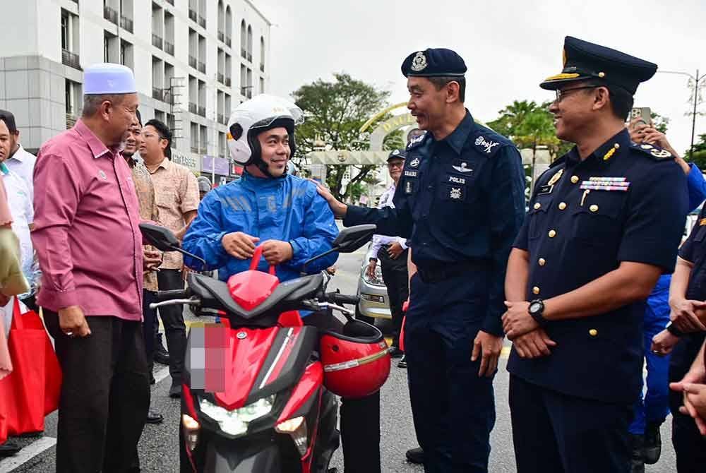 Mohd Khairi (dua dari kanan) beramah mesra dengan seorang penunggang motosikal ketika Kempen Keselamatan Jalan Raya Tahun Baru Cina 2025 Peringkat Negeri Terengganu di Dataran Shah Bandar, Kuala Terengganu pada Ahad.