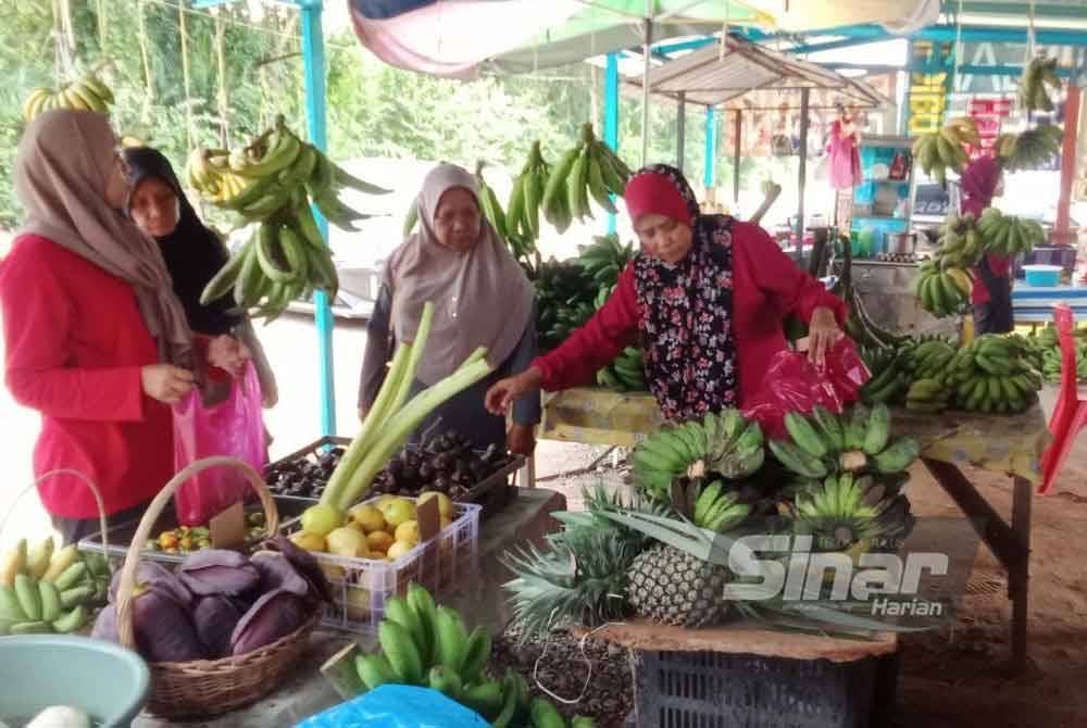 Che N Intan (kanan) ketika menguruskan gerai jualannya.