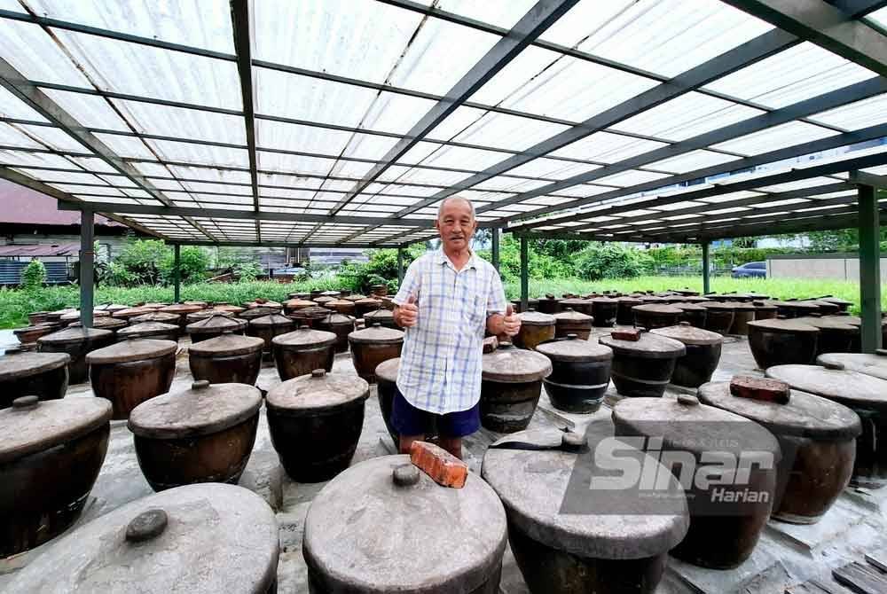 Pak Tong bersama deretan tempayan yang digunakan bagi menghasilkan kicap.