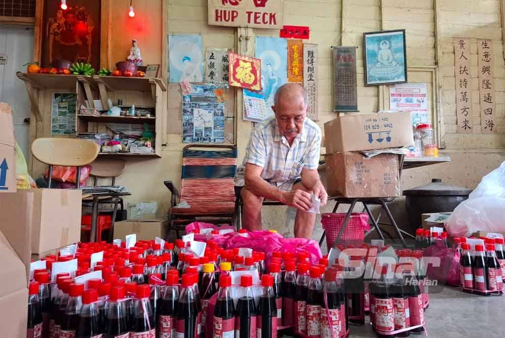 Pak Tong bersama stok terakhir kicap keluaran kilangnya sebelum menutup sepenuhnya operasi pada Selasa.