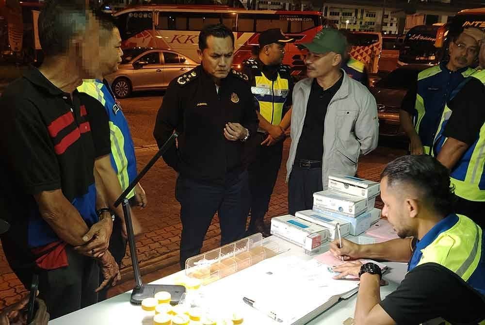 Azmi (kanan) meninjau proses ujian saringan air kencing ke atas pemandu bas di Terminal Bersepadu Selatan, pada Selasa.