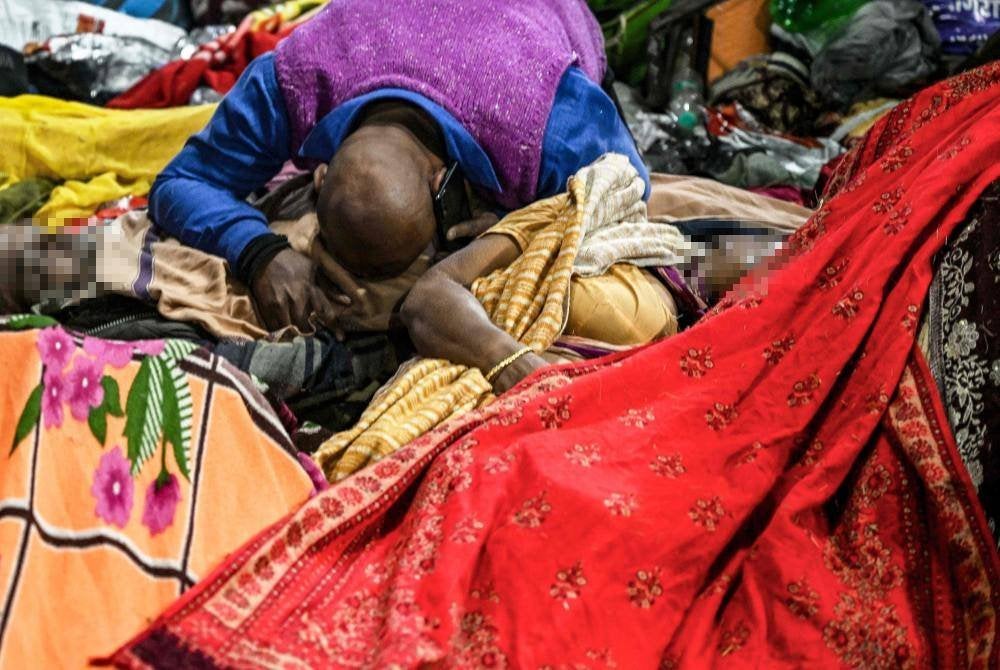 Seorang lelaki di sisi mayat dipercayai ahli keluarganya yang maut dalam rempuhan semasa Festival Hindu Maha Kumbh di negeri Uttar Pradesh, utara India. Foto AFP