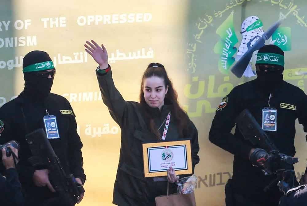 Agam Berger melambai ketika militan Hamas mengiringinya di atas pentas sebelum melepaskannya kepada pasukan Palang Merah di Jabalia. Foto AFP