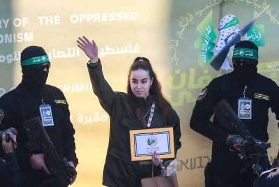 Agam Berger melambai ketika militan Hamas mengiringinya di atas pentas sebelum melepaskannya kepada pasukan Palang Merah di Jabalia. Foto AFP