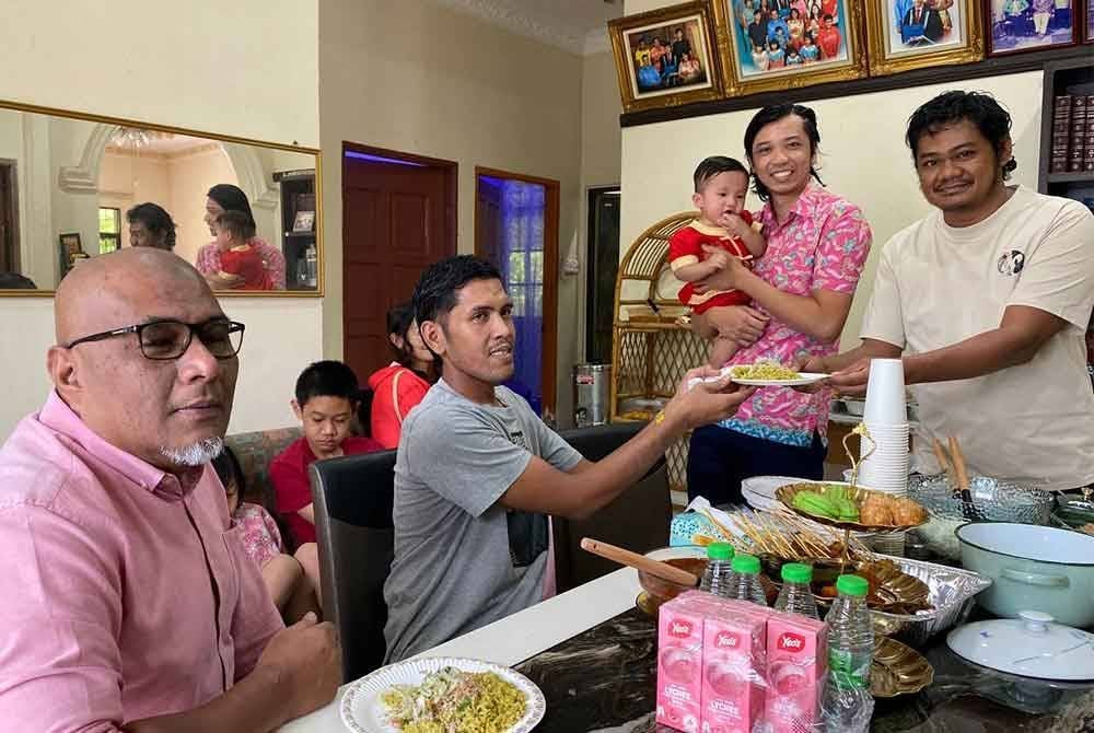 Iskandar (dua kanan) serta adiknya melayan tetamu yang terdiri kaum Melayu datang beraya di rumah mereka.