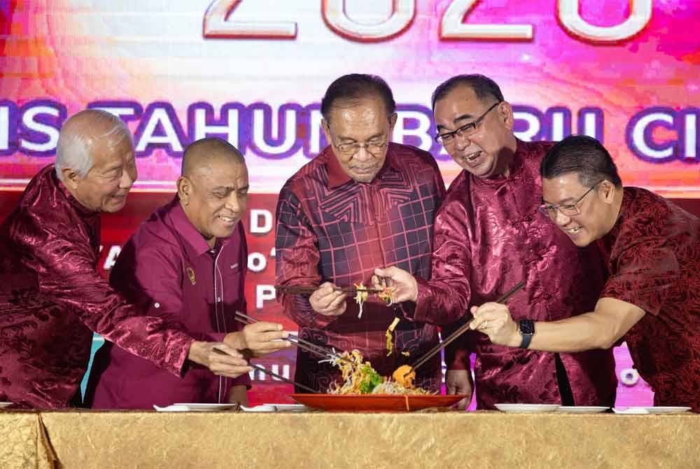 Anwar (tengah) menggaul yee sang ketika hadir pada sambutan Tahun Baharu Cina anjuran PCCCI pada Jumaat. Foto Bernama