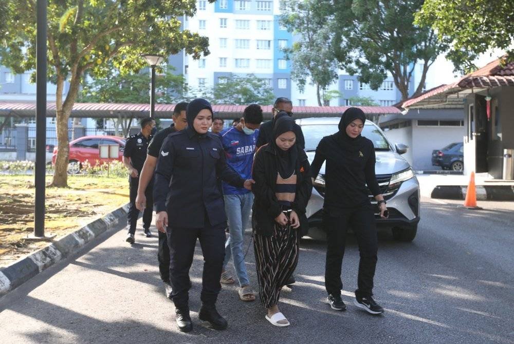 Pasangan kekasih berkenaan diiringi anggota polis sebaik tiba di pekarangan mahkamah.