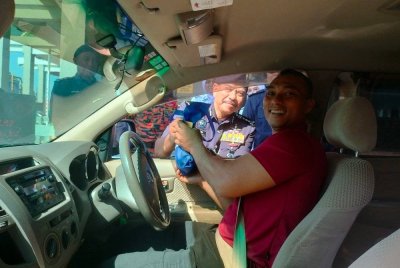 Hamzah (kiri) menyampaikan cenderahati kepada pengguna jalan raya sempena Program Advokasi sempena Op Selamat 23/2025 Tahun Baharu Cina Peringkat PDRM Kontinjen Pulau Pinang di Plaza Tol Sungai Dua arah Selatan di Sungai Dua pada Jumaat.