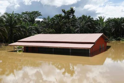 Sebuah rumah ditenggelami air dari limpahan air Sungai Labuk yang mengakibatkan banjir di Kampung Ganah Jati. Foto Bernama