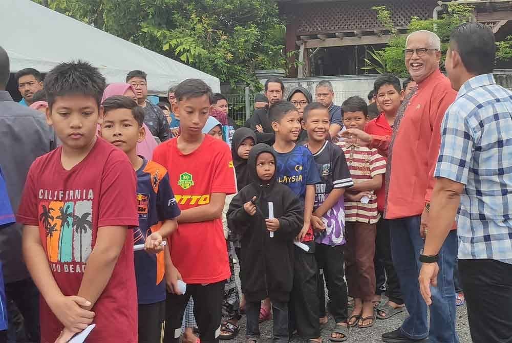 Mahfuz (dua dari kanan) beramah mesra dengan penerima pada Program Kembali ke Sekolah di Langgar pada Sabtu.