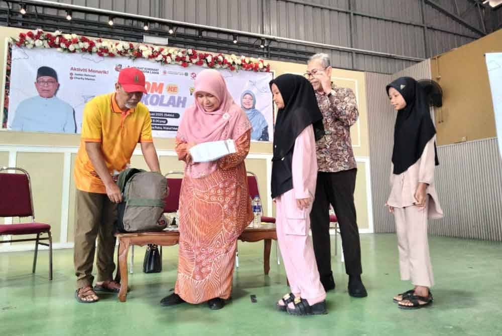 Dr Hafidzah (dua dari kiri) melihat pakaian sekolah ketika Program Jom Ke Sekolah di Sekolah Kebangsaan (SK) Tengku Indera Petra pada Sabtu.