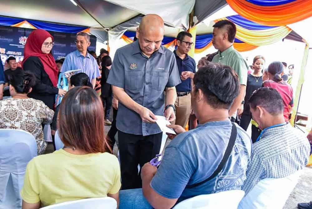 Armizan menyampaikan bantuan program outreach yang diadakan di Taman Keramat, Likas.