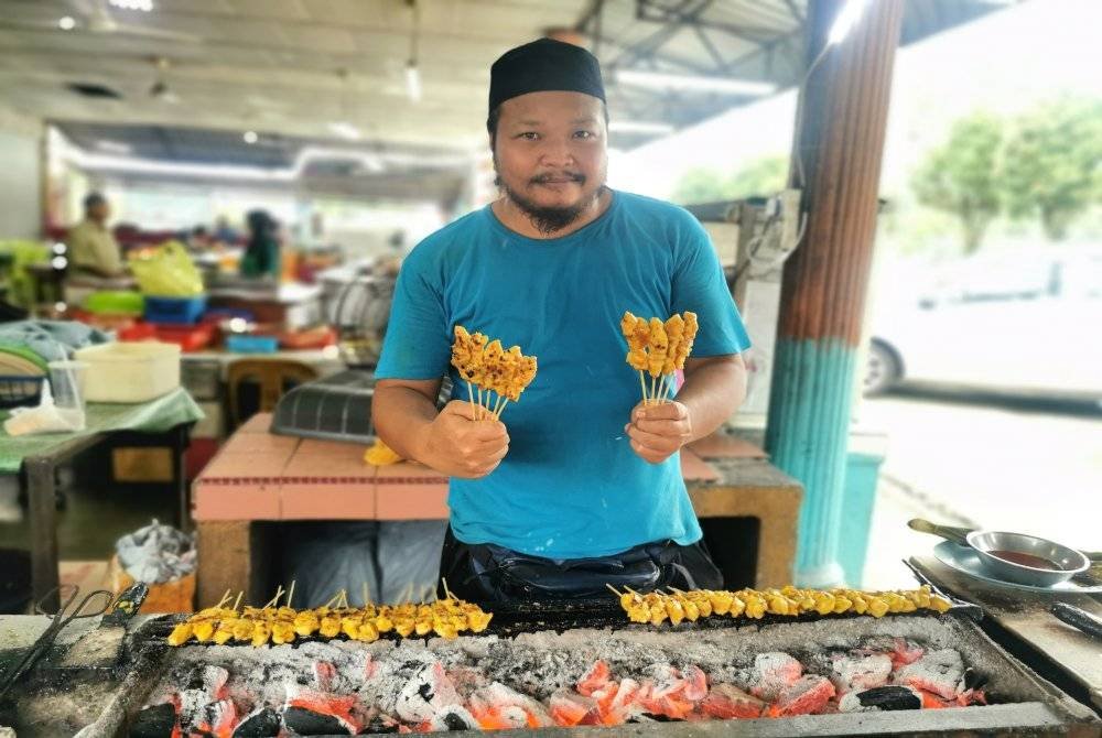 Norhisham menyediakan sate yang ditempah pelanggan.