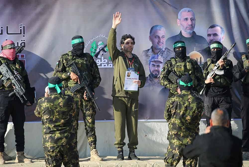 Pejuang Hamas mengiringi tebusan Israel-Perancis, Ofer Kalderon sebelum diserahkan kepada pasukan Palang Merah di Khan Yunis. Foto AFP