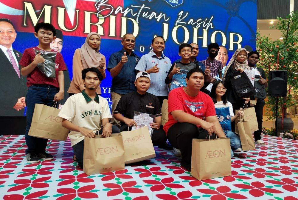 Aznan (berdiri empat dari kiri) bersama para pelajar pada Program Bantuan Kasih Murid Johor di AEON Mall Tebrau hari ini.