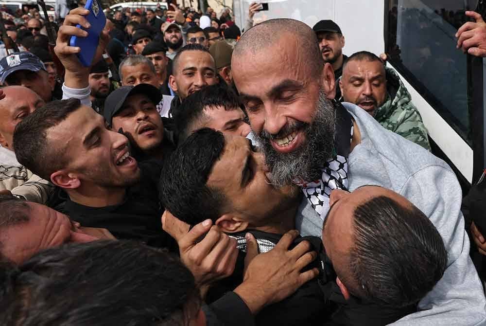 Seorang bekas tahanan Palestin yang dibebaskan oleh Israel dipeluk oleh ahli keluarganya ketika dia turun dari bas Palang Merah selepas tiba di Ramallah di Tebing Barat yang diduduki pada 1 Februari 2025. Foto AFP
