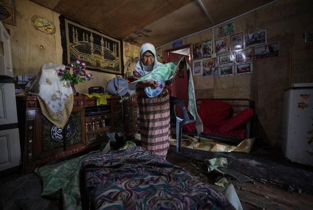 Warga emas, Aninah Abdullah, 73, membuang tikar getah rumahnya yang rosak akibat banjir ketika tinjauan di Kampung Gana Jati pada Jumaat. Foto Bernama