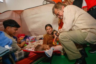 Abang Johari menyampaikan bantuan kepada penduduk Kampung Lereng Bukit yang terjejas akibat kejadian tanah runtuh di PPS Bulan Sabit Merah pada Jumaat. Foto Bernama