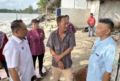 Aznan (kiri) berkata sesuatu kepada penduduk di Sungai Rengit.