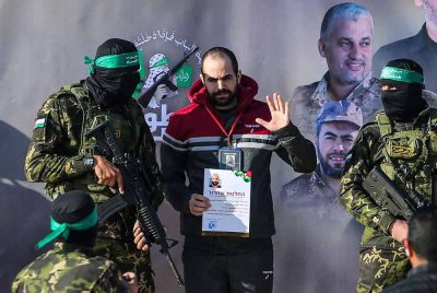 Pejuang Hamas mengiringi tebusan Israel, Yarden Bibas di atas pentas sebelum menyerahkannya kepada pasukan Palang Merah di Khan Yunis. Foto AFP
