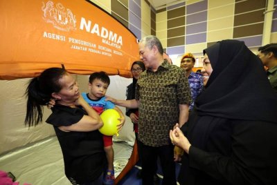 Fadillah dan isteri, Datin Seri Ruziah Mohd Tahir menyantuni mangsa banjir di PPS Dewan Haji Kamarudin Kampung Segedup pada Sabtu. Foto Bernama