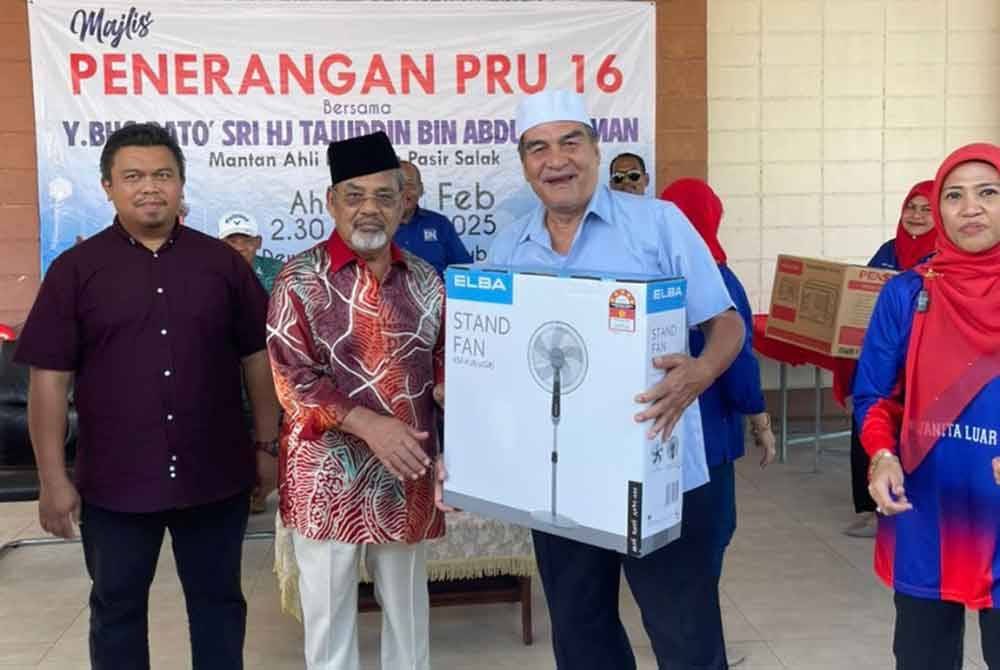 Tajuddin (dua dari kiri) menyampaikan hadiah cabutan bertuah kepada orang ramai yang hadir ke Majlis Penerangan PRU16 di Dewan Parit 9, Labu Kubong di sini pada Ahad.
