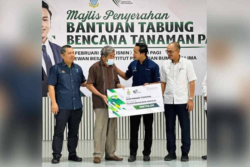 Fahmi (dua dari kanan) menyampaikan cek cura kepada salah seorang petani pada Majlis Penyerahan Bantuan Tabung Bencana Tanaman Padi Pulau Pinang pada Isnin.