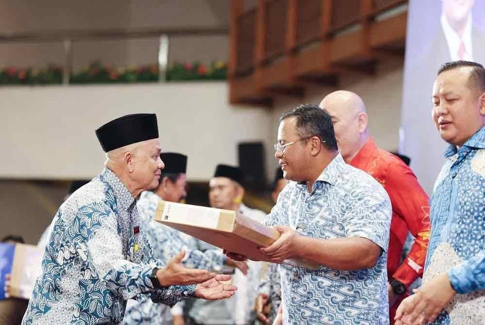Amirudin (kanan) menyampaikan komputer riba kepada ketua kampung bagi meningkatkan produktiviti dan kecekapan teknologi. Foto: FB Amirudin Shari.