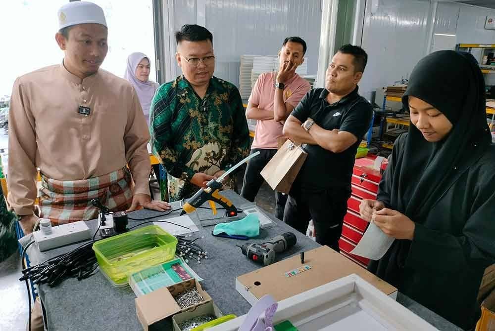 Mohammad Yaakub Yusra (kiri) menunjukkan proses penghasilan jam azan digital di bengkel yang dibangunkan di Madad, Kedah.