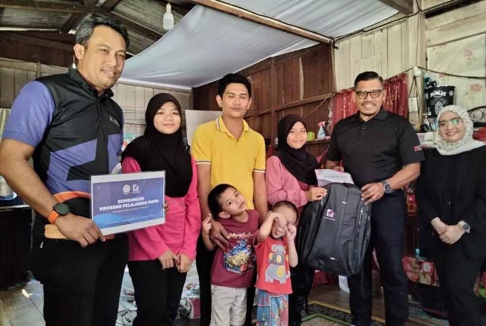 Nur Nasuha (tiga, kanan) menerima sumbangan daripada Zainal Rashid yang menyantuni keluarganya pada Isnin.