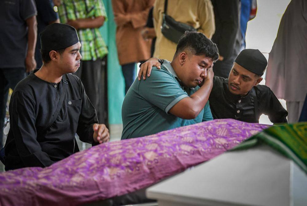 Amsyar Zahran, 23, (dua dari kiri) begitu pilu semasa menatap buat kali terakhir jenazah adiknya sebelum disolatkan di Masjid Al Muttaqin hari ini. Foto Bernama