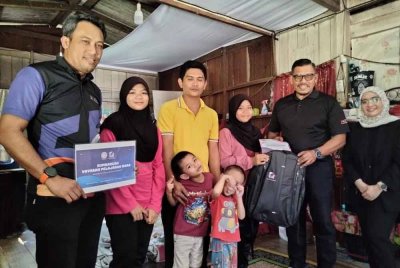 Nur Nasuha (tiga, kanan) menerima sumbangan daripada Zainal Rashid yang menyantuni keluarganya pada Isnin.