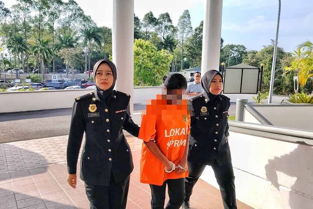 Suspek (tengah) ketika tiba di Mahkamah Majistret Melaka pada Selasa.