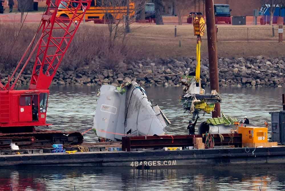 Sebuah kren besar digunakan untuk mengangkat serpihan badan pesawat dari dasar sungai. Foto AFP