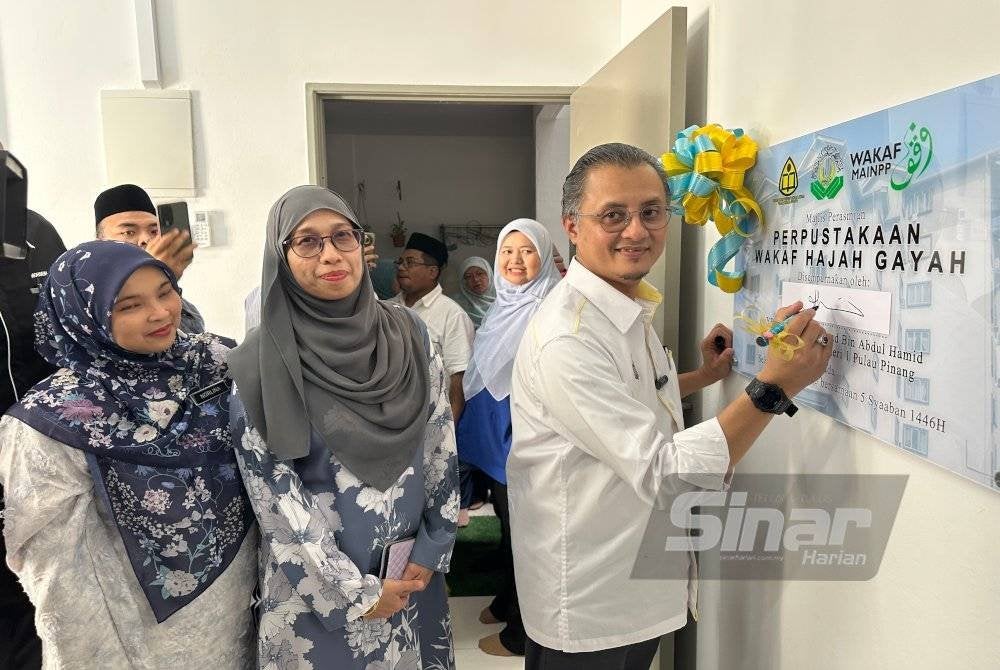 Mohamad menandatangani plak di Perpustakaan Wakaf Hajah Gayah di Pangsapuri Warisan Tanjung pada Selasa.
