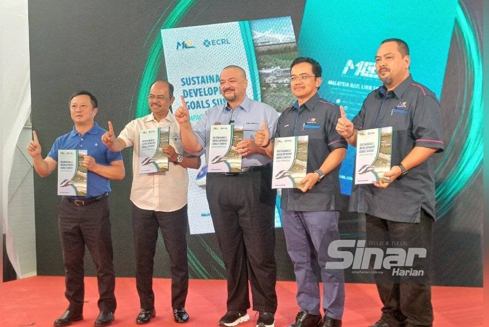 Amir Hamzah (tengah) menunjukkan buku laporan majlis pelancaran laporan impak terkini Sukuk Matlamat Pembangunan Mampan (SDG) bagi Projek ECRL di tapak projek ECRL Seksyen 10 pada Selasa. Foto SINAR HARIAN