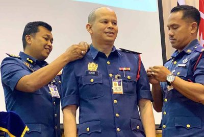 Farhan Sufyan (kiri) memakaikan tanda pangkat kepada Penolong Kanan Penguasa Bomba, Shapawi Stapa (tengah) dari Bahagian Keselamatan Kebakaran pada Perhimpunan Bulan JBPM Kelantan di Kota Bharu pada Selasa.