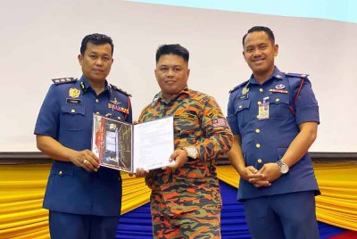 Farhan Sufyan (kiri) menyampaikan sijil kepada bomba sukarelawan pada Perhimpunan Bulan JBPM Kelantan di Kota Bharu pada Selasa.