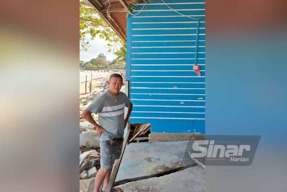 Beng Seng menunjukkan bahagian belakang rumahnya yang terjejas akibat hakisan ombak.