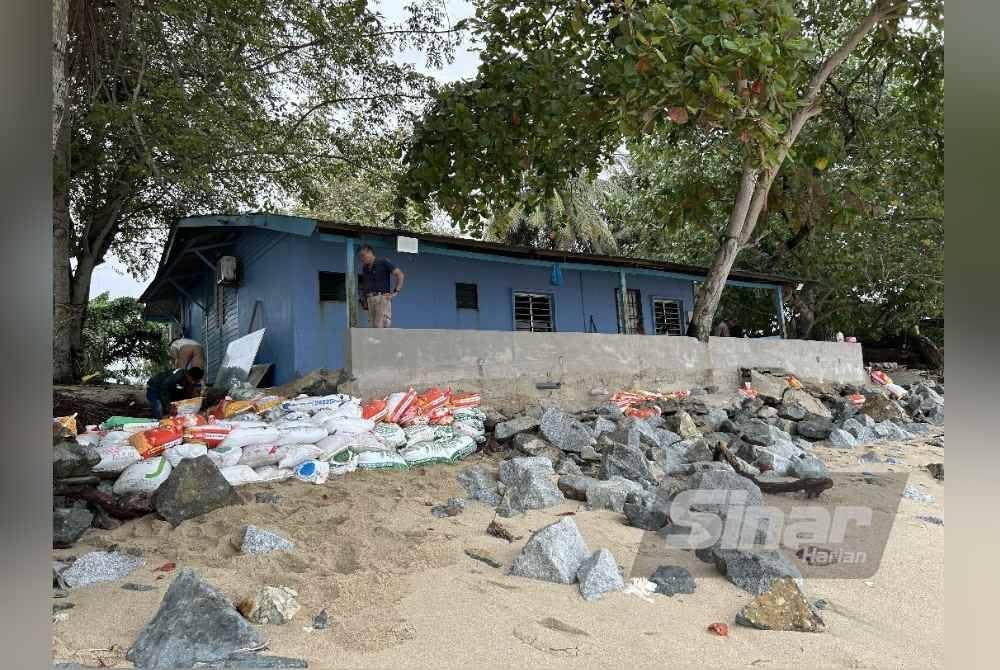 Seng Chea membina tembok dan meletakkan batu besar di belakang rumahnya sebagai usaha menahan hakisan ombak di belakang rumahnya.