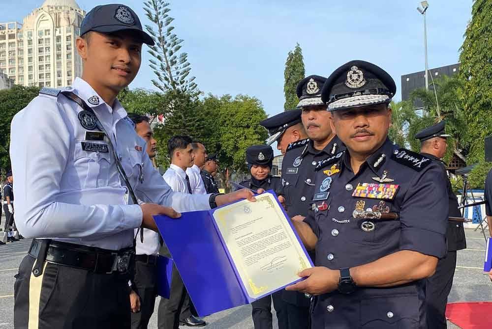 Mohd Yusoff (kanan) menyampaikan surat penghargaan kepada anggota semasa Perhimpunan Bulanan Peringkat Ibu Pejabat Polis Kontinjen (IPK) Kelantan di Kota Bharu pada Rabu.