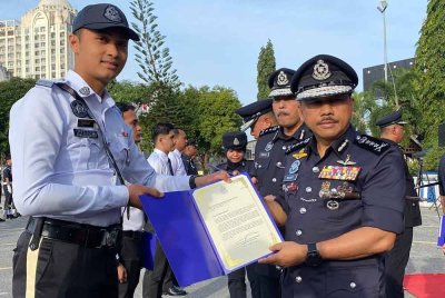 Mohd Yusoff (kanan) menyampaikan surat penghargaan kepada anggota semasa Perhimpunan Bulanan Peringkat Ibu Pejabat Polis Kontinjen (IPK) Kelantan di Kota Bharu pada Rabu.