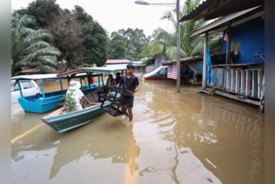 Seorang penduduk mengangkat barangan rumahnya untuk berpindah selepas dinaiki air banjir ketika tinjauan di Pangkalan Bukit Garam semalam. Foto Bernama