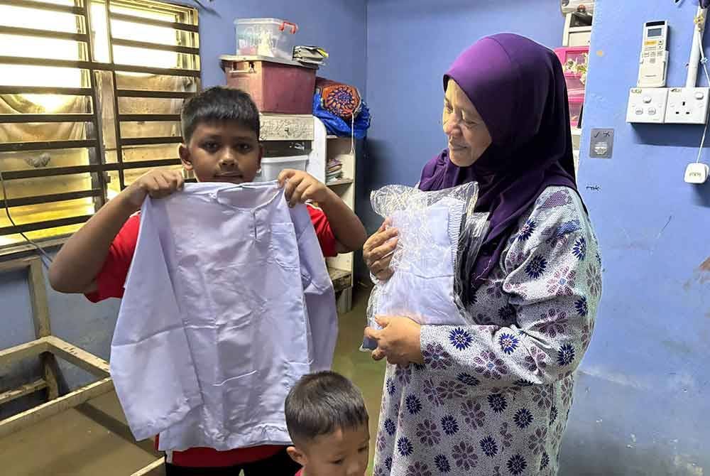 Abdul Waris Mohd Najib, 12, menunjukkan baju sekolah agama yang sempat diselamatkan ketika banjir pada awal pagi Rabu.