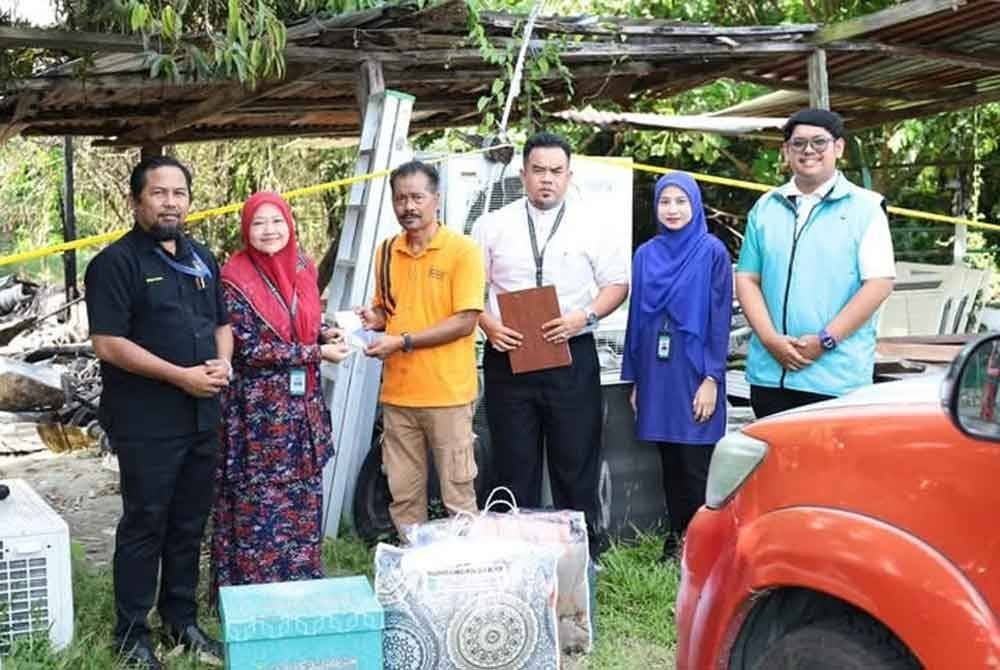 Wakil MAINS menyampaikan sumbangan kepada Azhar (tiga dari kiri) pada hari kejadian. Foto MAINS